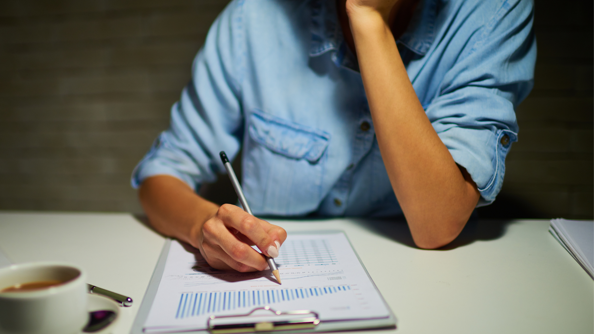 person at table working on paperwork with sleeves rolled